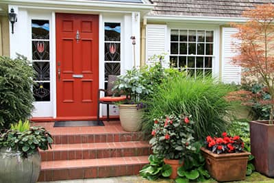 front of a home with a red front door and brick porch